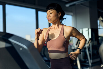 Focused Woman Running on Treadmill in a Modern Fitness Gym