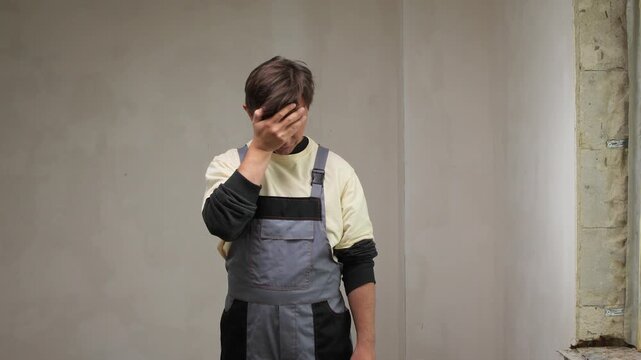 Frustrated construction worker touching forehead expressing disappointment during renovation