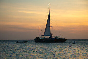 Sailboat anchored peacefully at sunset near a calm shoreline in tropical waters