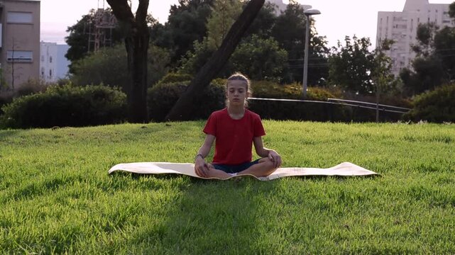 Girl in red tshirt practice yoga on mat,  meditating outdoors during school activity, meditation, exercise, fitness, mindfulness
