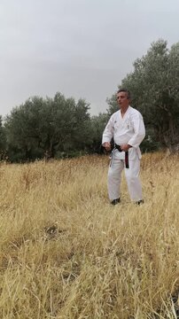 master practicing martial art outdoor in karate unifrom (white kimono), showing kata, view from the top, healthy lifestyle 