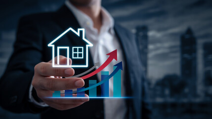 A professional business concept image showing a hand in a white dress shirt and black suit holding glowing digital house icons and financial graphs.