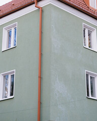 Travel through the old town, architecture and sights. A green building with a red roof and white trim. The building has many windows and a red roof.