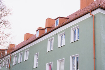 Travel through the old town, architecture and sights. A green building with a red roof and white trim. The building has many windows and a red roof.