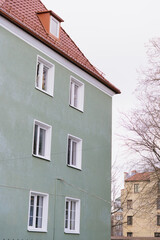 Travel through the old town, architecture and sights. A green building with a red roof and white trim. The building has many windows and a red roof.