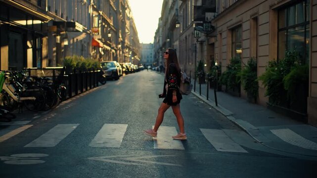 Woman tourist crossing pedestrian crossing walking through the streets of Paris. Beautiful architecture of the capital of France, walking through historical tourist attractions.