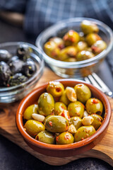Tapas. Flavored pickled olives in bowl on cutting board.