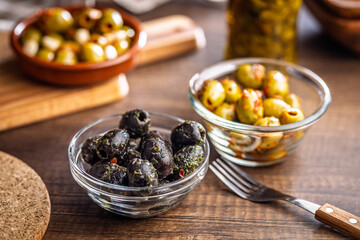 Tapas. Flavored pickled olives in bowl on wooden table.
