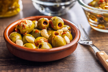 Tapas. Flavored pickled olives in bowl on wooden table.