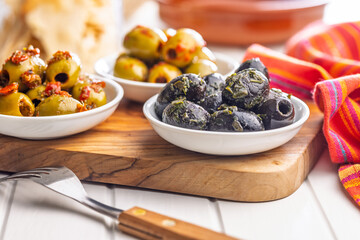 Tapas. Flavored pickled olives in bowl on cutting board.