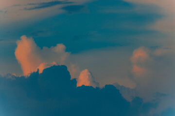 Dramatic cumulus clouds lit by golden sunset light against a darkening blue sky, creating a moody and atmospheric scene.
