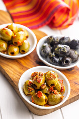 Tapas. Flavored pickled olives in bowl on cutting board.
