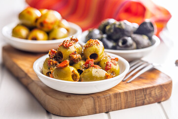 Tapas. Flavored pickled olives in bowl on cutting board.