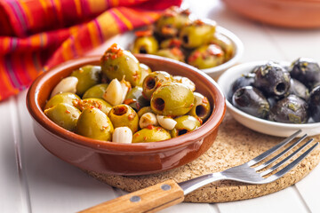 Tapas. Flavored pickled olives in bowl on white table.