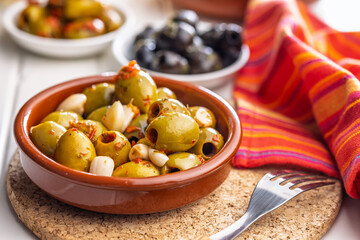 Tapas. Flavored pickled olives in bowl on white table.