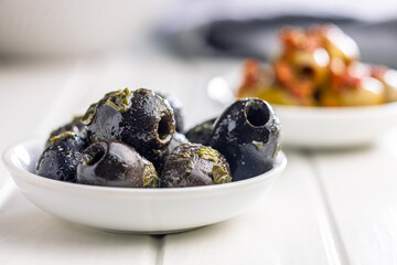 Tapas. Flavored pickled olives in bowl on white table.