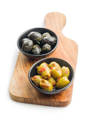 Tapas. Flavored pickled olives in bowl on cutting board isolated on white background.