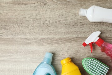 Various cleaning products including brush, sponge, spray on wooden background. Flat lay cleaning...