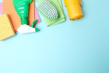 Household cleaning supplies including brush, sponges and bottles arranged in a frame on a blue...