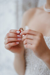 Elegant bride holding a wedding ring in preparation for her special day indoors