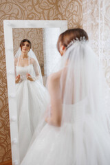 Bride admiring herself in a mirror before the wedding ceremony in an elegant venue