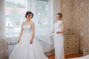 Bride getting ready for the wedding ceremony with a bridesmaid assisting in preparation