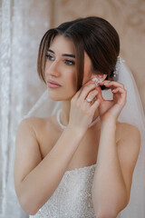 Bride preparing for the wedding ceremony while putting on earrings indoors