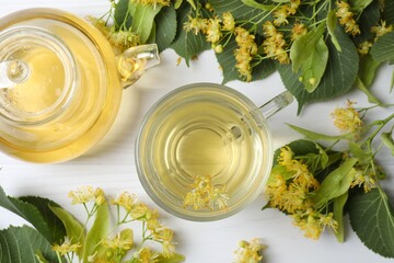 Top view of green tea with fragrant linden in teapot and white cup on white background
