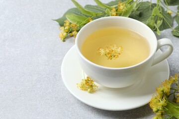Aromatic green tea with fragrant linden in white cup on gray background