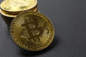Gold Bitcoin coins on a black background. Electronic decentralized money concept. 