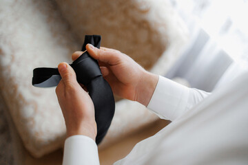 Preparing for a formal event with a black tie in a cozy indoor setting