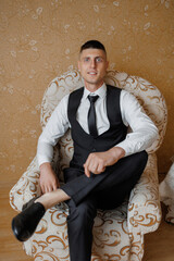 Smartly dressed man sitting in an elegant chair at a cozy indoor space