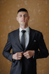 Young man adjusts suit jacket in stylish indoor setting before special event