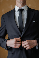 Man adjusting suit jacket in elegant indoor setting before formal event