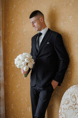 Groom holding bouquet in formal attire before wedding ceremony in elegant setting