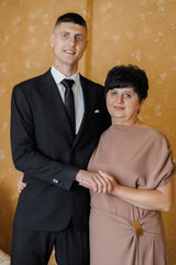Mother and son celebrate a special occasion together in a formal setting wearing elegant attire
