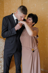 Young man shares a tender moment with his mother during a formal celebration indoors