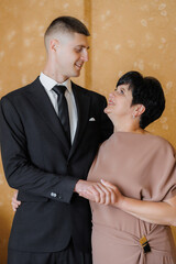 Mother and son share a joyful moment at a formal event in a warm-toned indoor setting