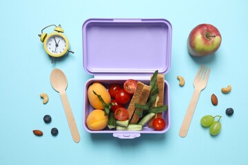 Colorful lunchbox filled with healthy snacks including fruits, vegetables, nuts, and a sandwich on a vibrant blue background