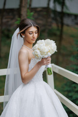 Bride holding bouquet of white flowers in outdoor setting during daytime
