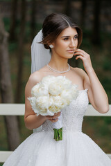 Bride holding bouquet of white flowers in a serene outdoor setting during daylight