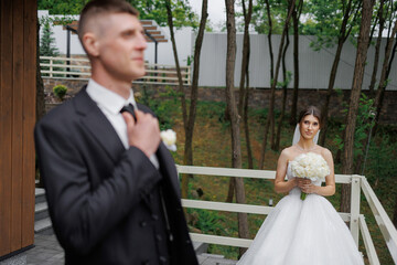 Couple preparing for wedding ceremony in lush outdoor setting near a modern venue