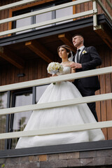 Couple in wedding attire on a balcony during a romantic moment near a wooden cabin