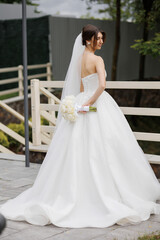 Bride in elegant wedding gown poses gracefully outdoors during the daytime