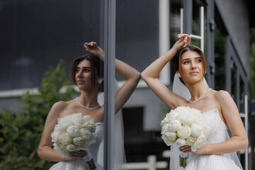 Bridal portrait in elegant attire with flowers near reflective surface