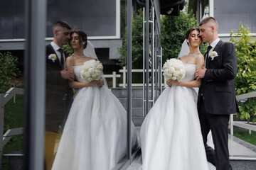 Elegant couple shares moment by modern venue reflecting their love and joy on wedding day