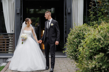 Elegant wedding couple walking hand in hand outside a venue on their special day