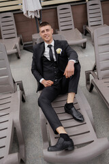 Man relaxing in a suit on a lounge chair by the pool in warm weather