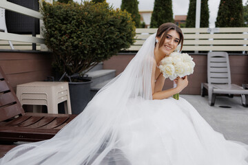 Bride poses elegantly with bouquet in outdoor setting during wedding ceremony