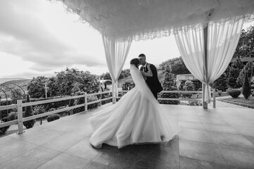 Couple shares a romantic first dance at an outdoor wedding venue in soft, natural lighting